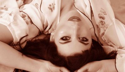 Femme allongée regardant l’objectif, maquillée et confiante, illustrant une animation autour de l’estime de soi et de la féminité assumée